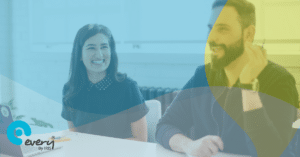 A smiling lady sat next to a smiling man smiling man at a table. An Every HR By IRIS gradient overlays the image.